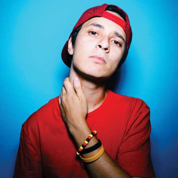 Photo of rapper DOBBY wearing a red tshirt and hat with his arm rested on his neck