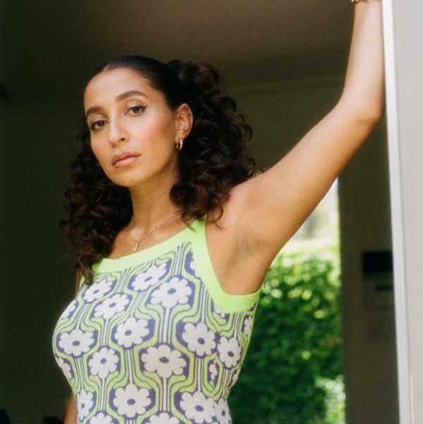 Photo of female musician WAFIA standing in a doorway wearing a printed check top