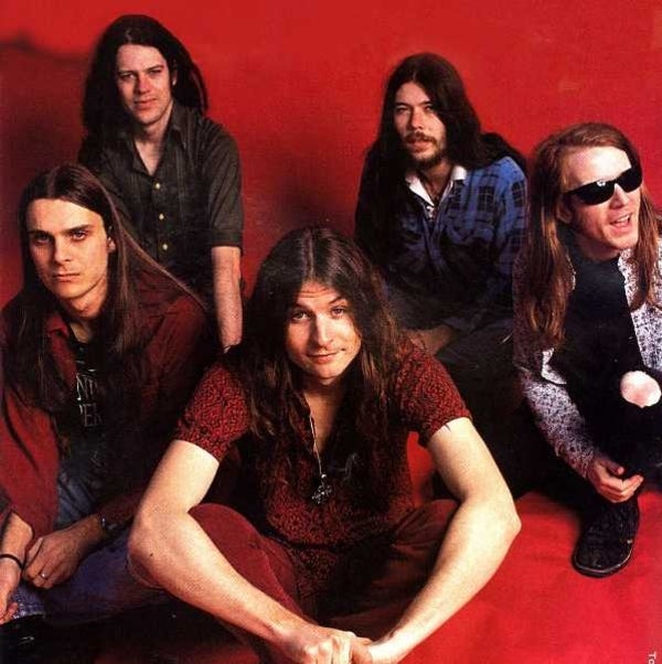 Photo of Tumbleweed band crouching down on a red studio wall